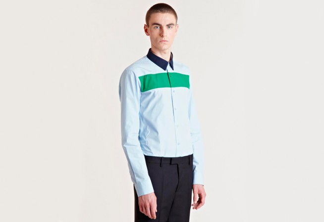 Camisa de algodão azul clarinho, com silhueta slim e jogo de cores entre a gola, a camisa e a faixa no peito. À venda por R$ 759 (câmbio do dia) no e-commerce LNCC