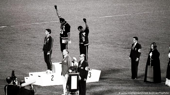 Tommie Smith (centro) e John Carlos em protesto nos Jogos da Cidade do México, em 1968 / Foto: Reprodução